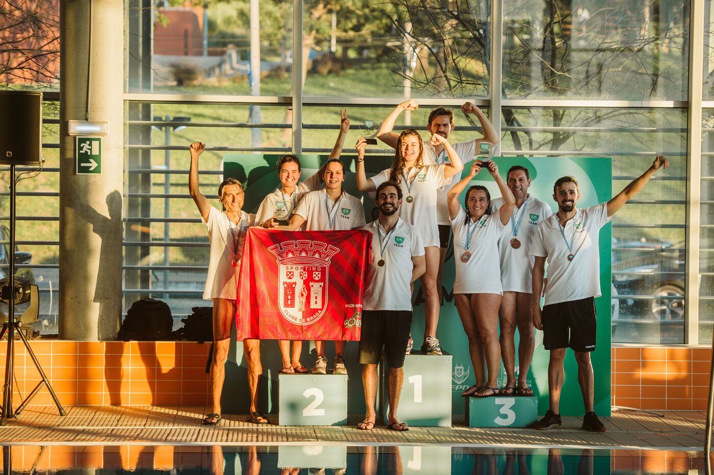 Winners' podium with arms raised at the EA Team / ANEA Swimming Tournament