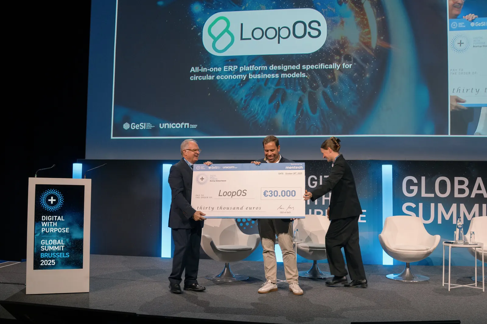 Entrega de prémio em palco, com cheque simbólico entregue a uma startup