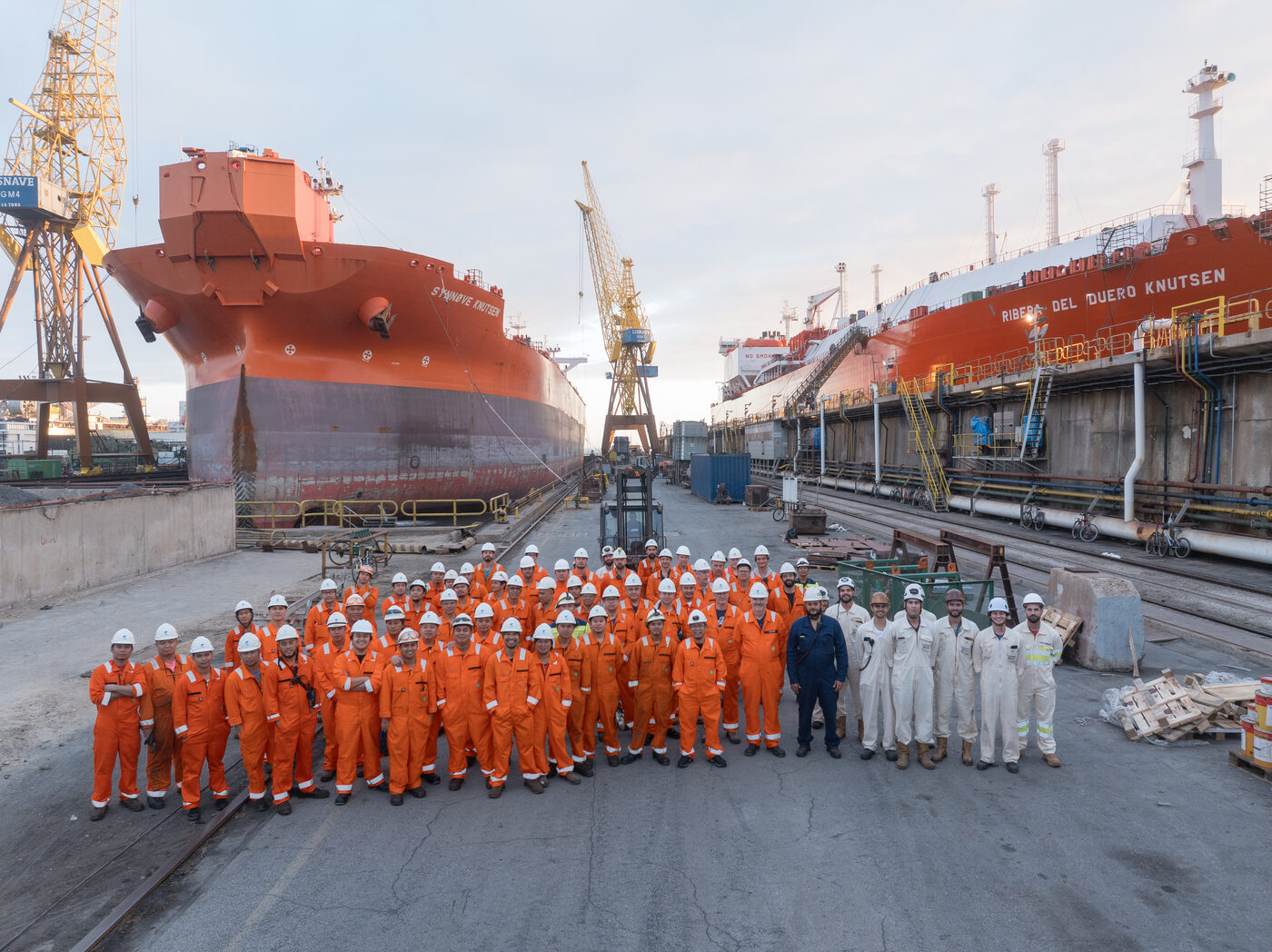 Foto de grupo da equipa do estaleiro de Setúbal em frente a um navio em reparação