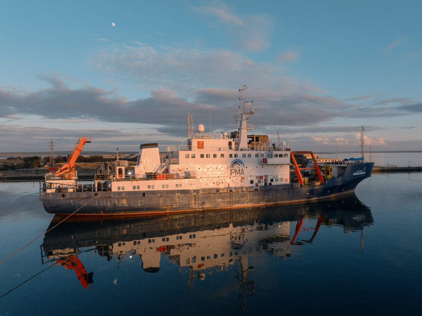 Navio em doca no estaleiro de Setúbal ao amanhecer, com reflexo na água, vista aérea de drone