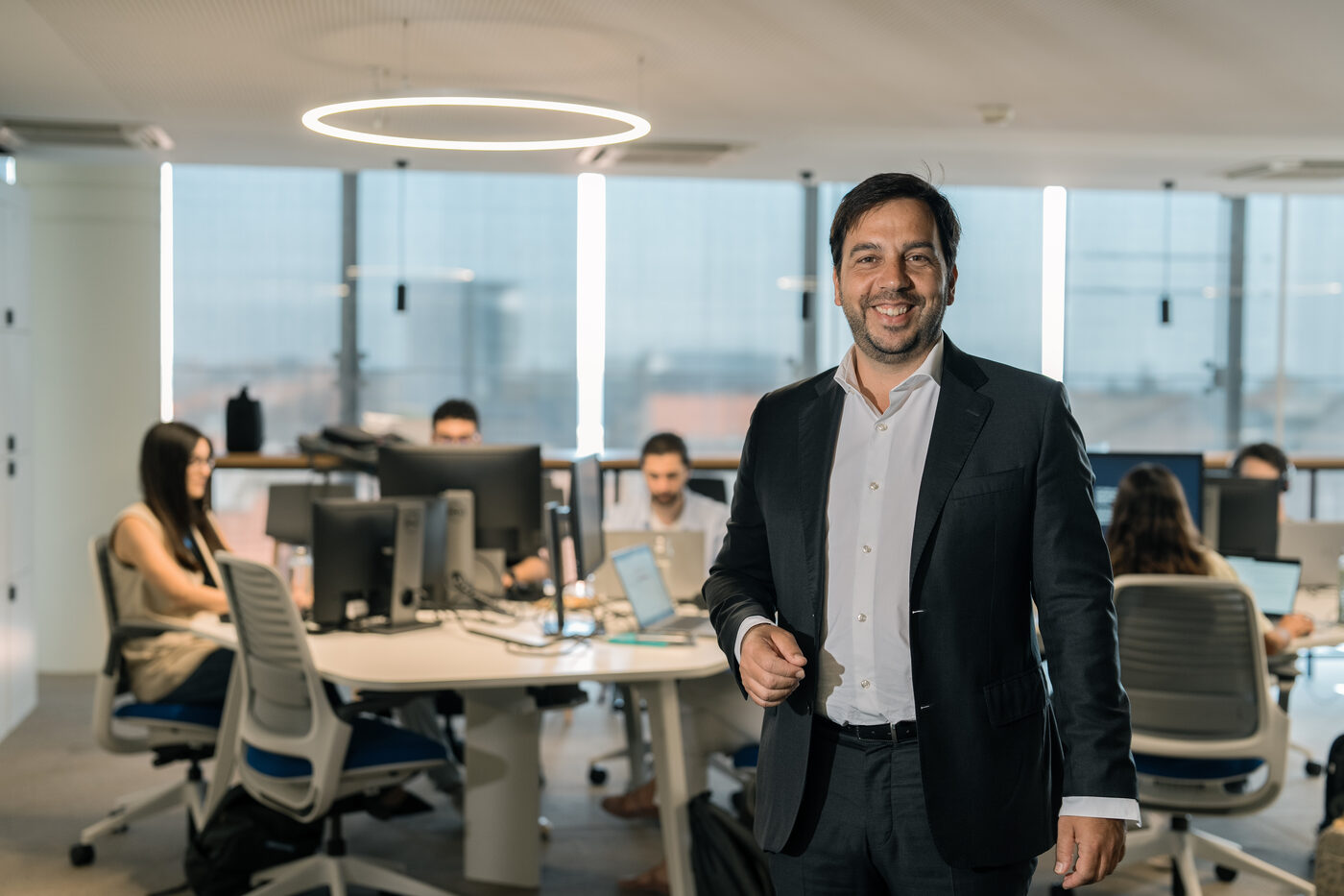 Retrato corporativo de homem de fato em open space de escritório, fotografia para perfil de empresa