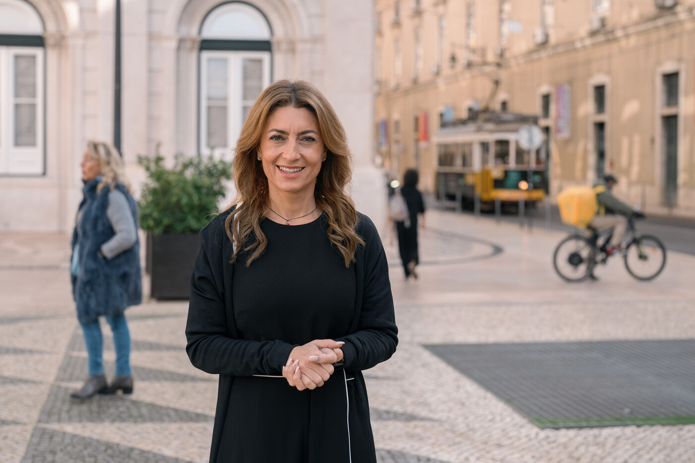 Retrato corporativo de mulher numa rua de Lisboa com elétrico ao fundo, fotografia em exterior
